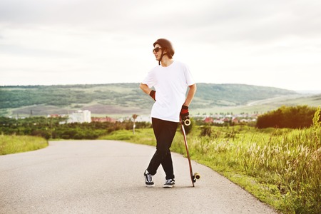 A young guy - a skater standing in anticipation of a race on a country roadの写真素材