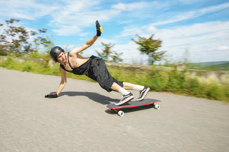 Young man in helmet is going to slide, slide with sparks on a longboard on the asphaltの写真素材