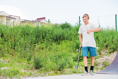 The boy is standing in the skatepark and showing the likes