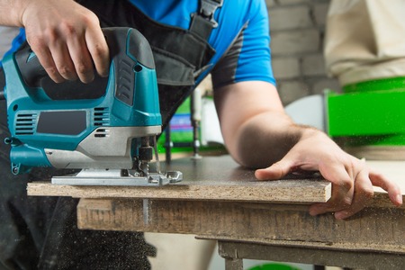 Close-up carpenter working with an electric jigsaw