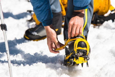 A young guy hiker dresses climbing Crampons over mountaineering shoes For walking through Glacierの写真素材