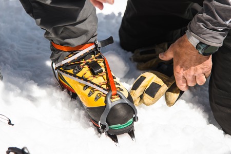 A young guy hiker dresses climbing Crampons over mountaineering shoes For walking through Glacierの写真素材