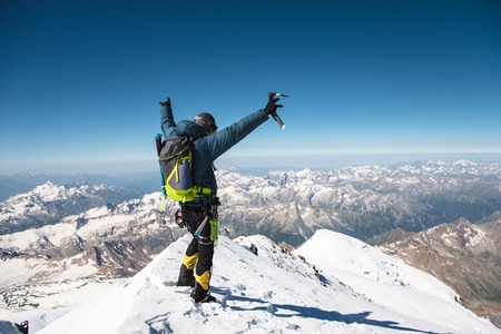 Professional guide Hiker at the top of the rock with his hands up is pleased with the next victory of the ascentの写真素材