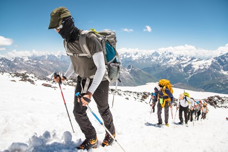 A group of mountaineers climbs to the top of a snow-capped mountainの写真素材