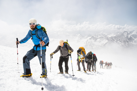 A group of mountaineers climbs to the top of a snow-capped mountainの写真素材
