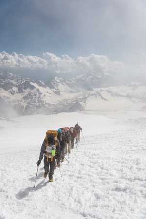 A group of mountaineers climbs to the top of a snow-capped mountainの写真素材