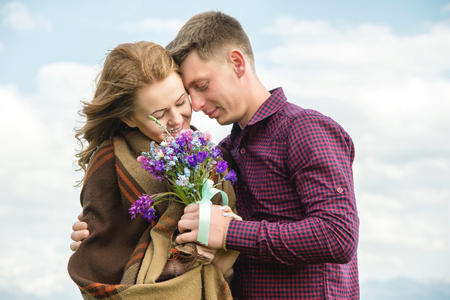 Young couple in love embraces gently against the blue sky and white cloudsの写真素材
