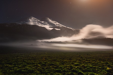 A floating cloud in the vicinity of the sleeping Elbrus volcano in the Caucasus at night in the light of the moonの写真素材