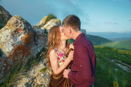 Young happy couple kissing on nature against the beautiful Caucasian landscape.の写真素材
