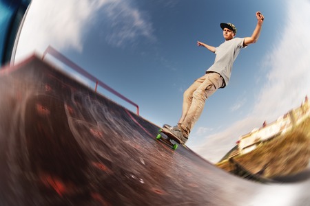 Teen skater hang up over a ramp on a skateboard in a skate parkの写真素材
