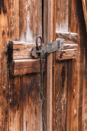 old simple lock on a wooden door closed with a metal pin rustic latch on an old door made of woodの写真素材