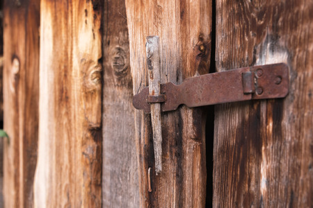 old simple lock on a wooden door closed with a metal pin rustic latch on an old door made of woodの写真素材