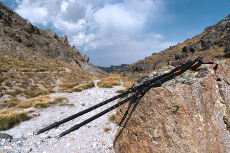 Professional sticks for climbing a mountain near a stone on a high mountain path against a blue sky and white clouds.の写真素材