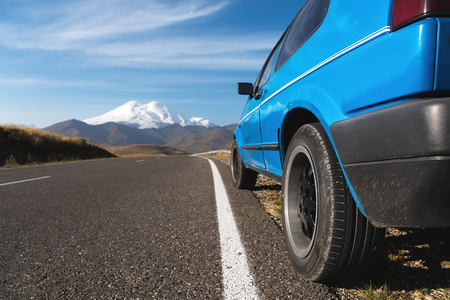 High mountain landscape with a blue car on the roadside. North Caucasus.の写真素材