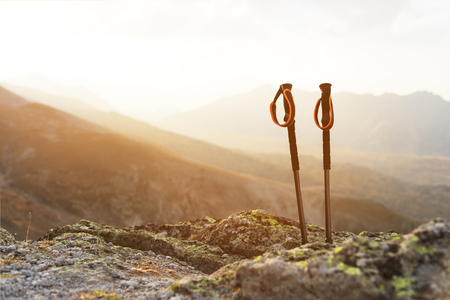 Professional sticks for climbing a mountain near a stone on a high mountain path against a blue sky and white clouds on sunsetの写真素材