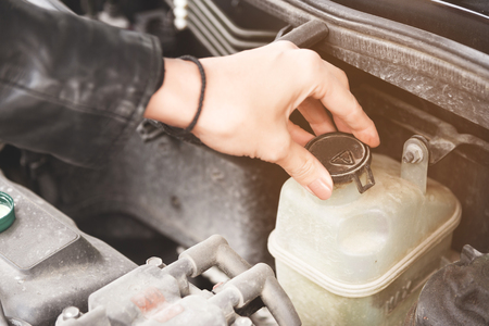Close up girl checks the level of coolant in the engine of her carの写真素材