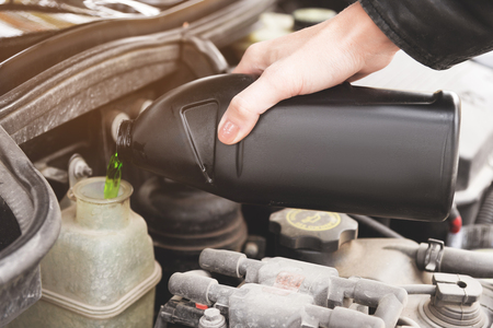Close up girl checks the level of coolant in the engine of her carの写真素材