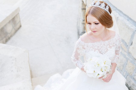 Portrait of a beautiful bride in a white dress and a bouquet of flowers in her handsの写真素材