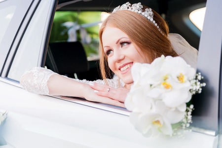 Close-up portrait of a beautiful bride in a wedding car window. The concept of wedding happiness.の写真素材