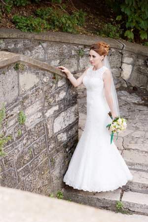 Portrait of a beautiful bride in a white dress and a bouquet of flowers in her handsの写真素材
