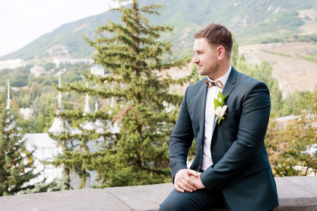 Portrait of a bearded hipper groom in a blue suit and a red tie at a wedding walkの写真素材