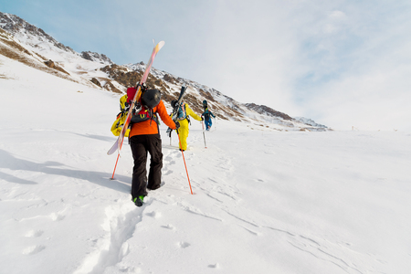 A group of three freeriders climb the mountain for backcountry skiing along the wild slopes of theの写真素材