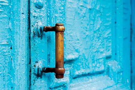 Close-up keyholes with curtains and a handle on the blue many times painted cracked double-barreled wooden vintage door of the last century with a post slit.の写真素材