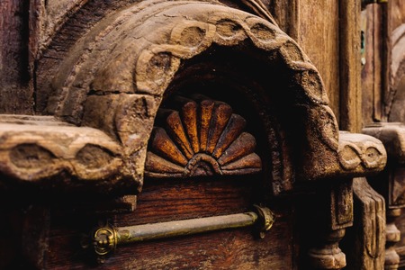 Vintage background. Elements of an old carved wooden door decorated with voluminous carved wooden elements imitating the weaving. A vintage concept of old antiques. Varnished old mahoganyの写真素材