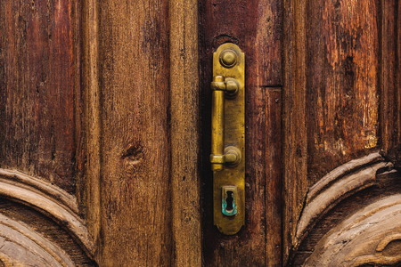 Vintage background. Brass-made old handle with Elements of an carved wooden door decorated with massive wooden simulating weaving.の写真素材