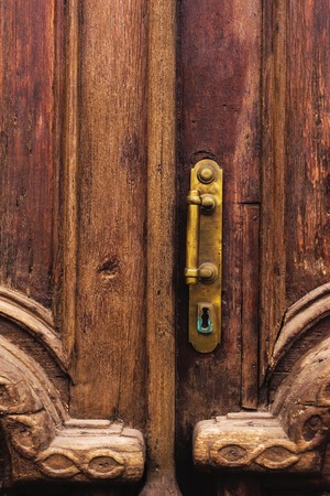 Vintage background. Brass-made old handle with Elements of an carved wooden door decorated with massive wooden simulating weaving.の写真素材