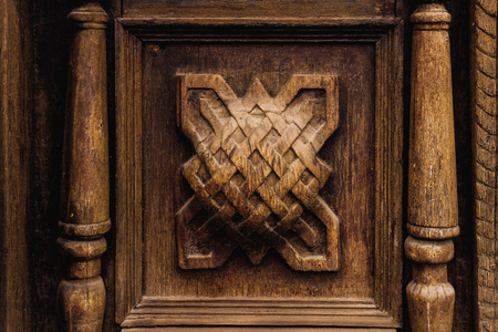 Vintage background. Elements of an old carved wooden door decorated with voluminous carved wooden elements imitating the weaving. A vintage concept of old antiques. Varnished old mahoganyの写真素材