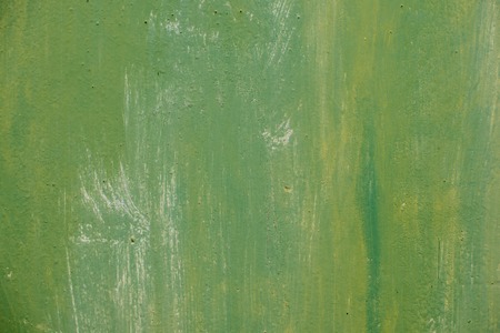 Textured metal surface carelessly colored green paint and faded in the sun in pale gray with rusty specks.の写真素材