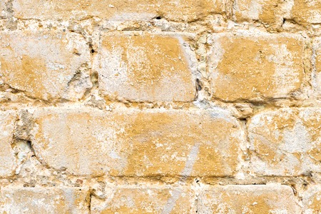 Close-up Textured background of a multi-colored brick painted in yellow. A sizzling yellow paint on...