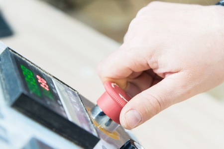 Close-up of a man's hand on a red button on the control panel. Emergency stop or start of equipment...