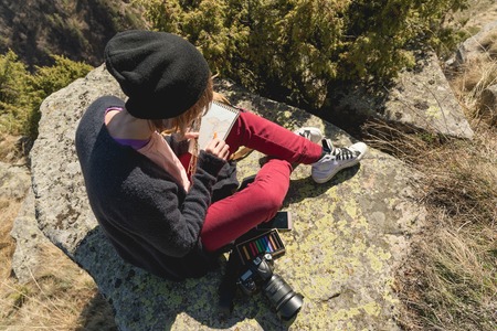 Portrait of a hipster designer photographer girl in hat and sunglasses draws a pastel in her...
