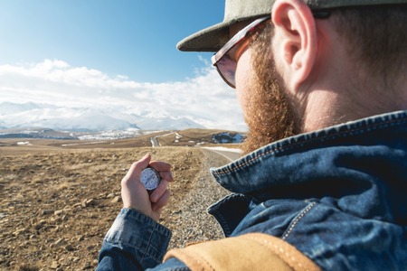 Close-up Hipster man using a compass on a snowy mountain
