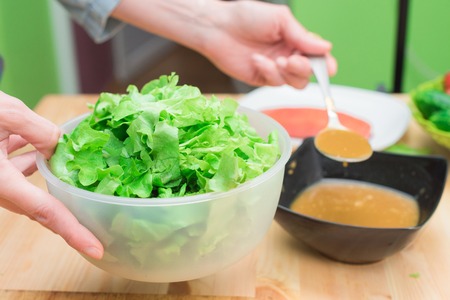 Female hands adding sauce to lettuce from lettuce leaves. Home kitchen. Tasty healthy and healthy foodの写真素材