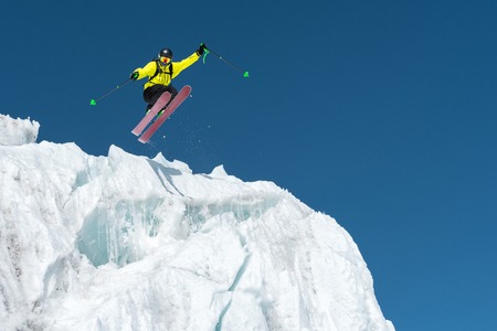 A jumping skier jumping from a glacier against a blue sky high in the mountains. Professional skiingの写真素材