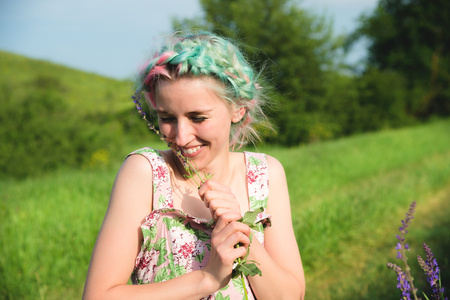Portrait of a young happy smiling girl in a cotton dress with a bouquet of wildflowersの写真素材