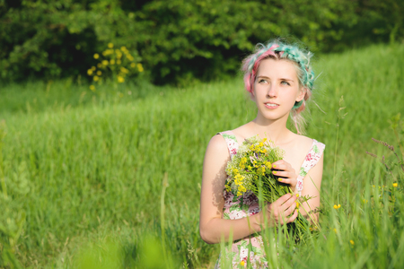Portrait of a young happy smiling girl in a cotton dress with a bouquet of wildflowersの写真素材