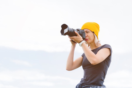 Portrait of a professional photographer in the open air. A girl photographer takes pictures of her...