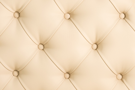 Beige soft tapestry pattern background with symmetrical buttons on the corners of diamonds. Soft and expensive furniture elements. Luxury backgroundの写真素材