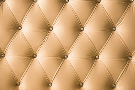 Beige soft textile background with symmetrical buttons on the corners of diamonds. Soft and expensive furniture elements. Luxury backgroundの写真素材