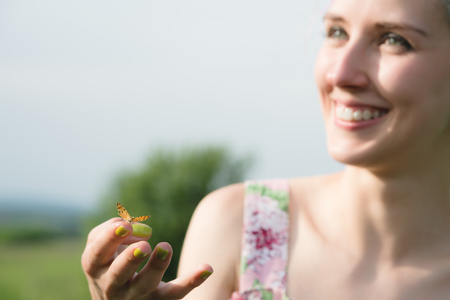 Portrait of a beautiful woman holding a butterfly on her hand in the garden. Beauty portrait. Unity with nature. Ecology conceptの写真素材
