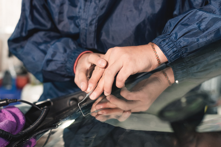 Close up Car glaze worker fixing and repairing a windshield or windshield of a car at a garage service station. Drill glass for repairの写真素材