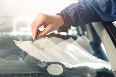 Close up Automobile glazier worker fixing and repair windscreen or windshield of a car in auto service station garageの写真素材