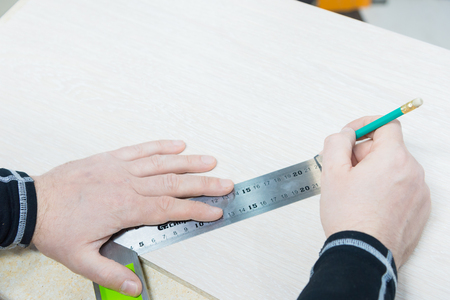 Close up Carpentry, mans hand using tape measure to measure wood plank and marking it with pencil. view from aboveの写真素材