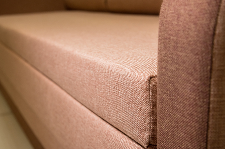 A close-up of a fragment of an expensive beige textile sofa in the roomの写真素材
