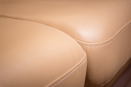 Close-up the Fragment of expensive beige leather sofa to indoors