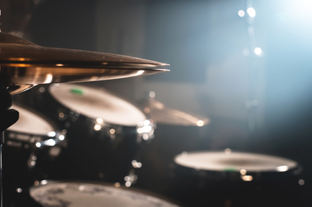 Close-up Drum set in a dark room against the backdrop of the spotlight. Atmospheric background symbol of playing rock or jazz drums. Copper plates on a cold backgroundの写真素材